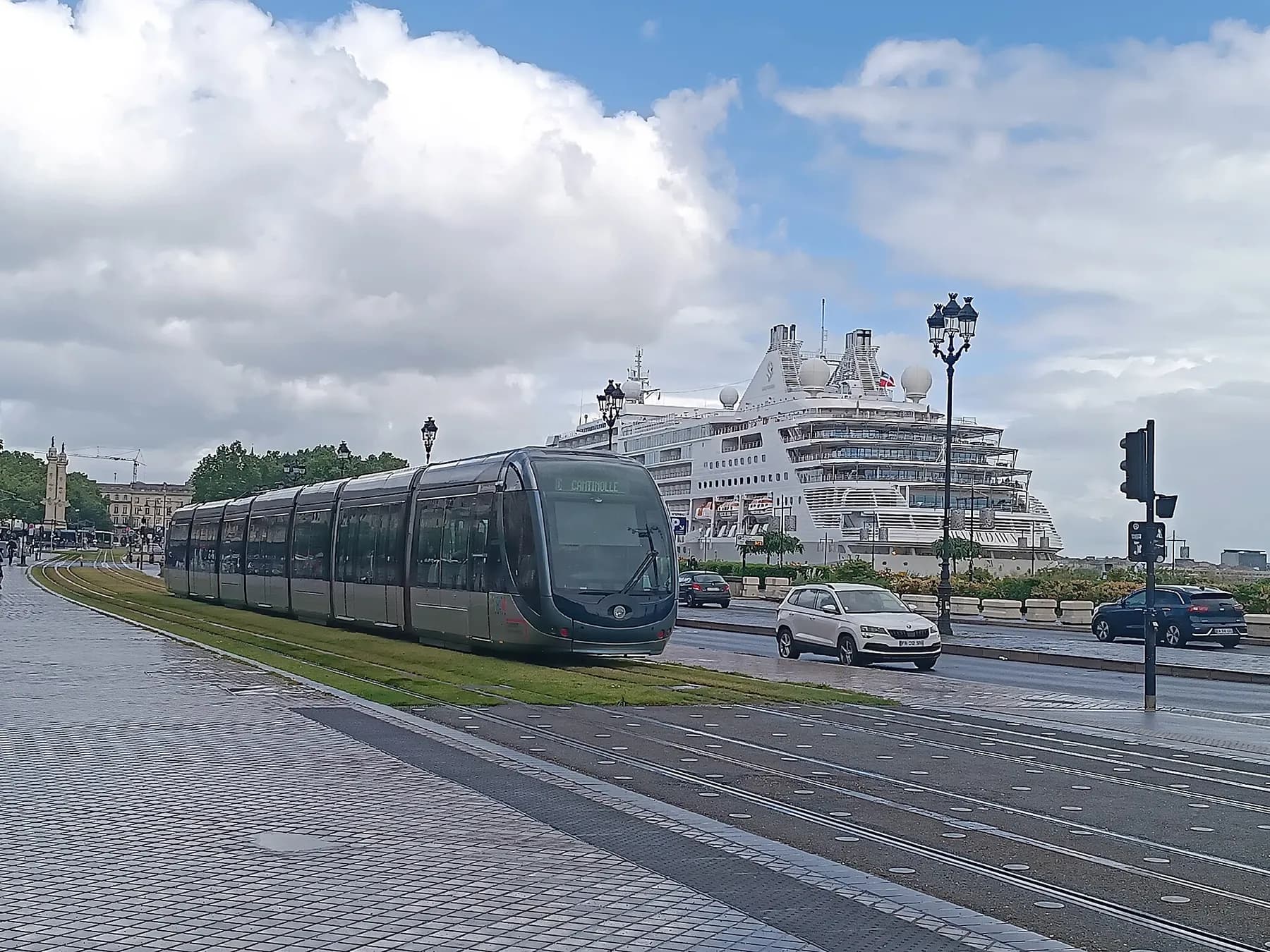 Un tram TBM longe les quais avec un paquebot en arrière-plan