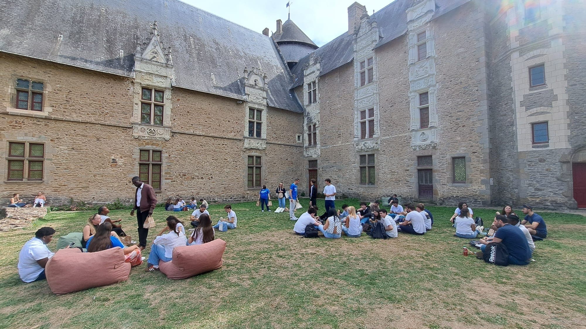 Étudiants assis sur la pelouse devant un château